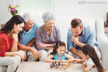 父母和祖父母看着女孩下棋