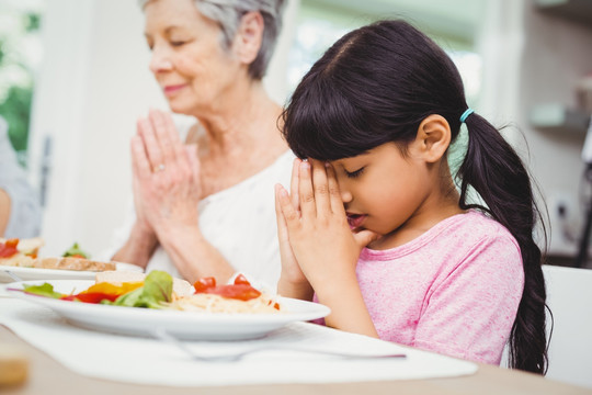 同奶奶在用餐前祈祷的母女