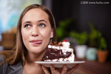 拿着一块蛋糕在咖啡馆里的女人
