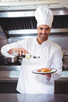 男厨师把橄榄油浇在沙拉上