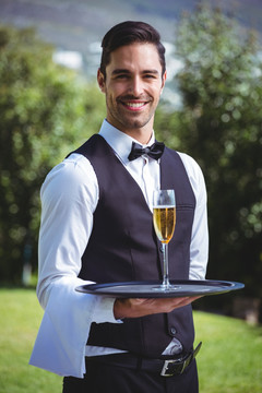 英俊的服务员拿着一杯香槟酒