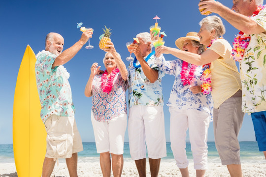 在沙滩上举着鸡尾酒的老年人们