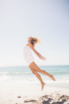 在沙滩上跳跃的金发女人