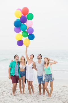站在沙滩上看着气球泡的朋友们