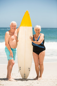 在海边老夫妇拿着冲浪板
