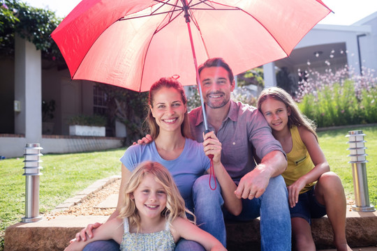 幸福的一家人坐在红伞下