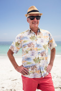 戴着帽子和墨镜站在海滩上的男人