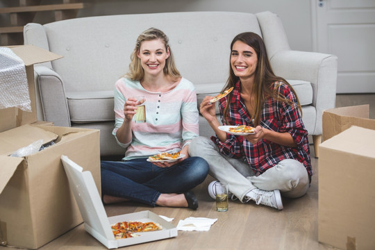 坐在新房子里吃披萨的两个女人