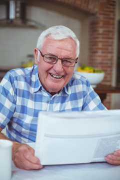 在厨房里阅读报纸的老人