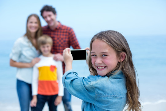女孩在海边给家人拍照