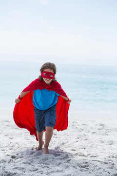 穿着超级英雄服装在海边的男孩