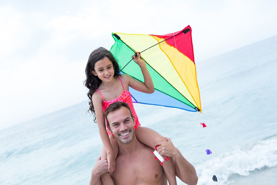带着女儿在海边放风筝的父亲