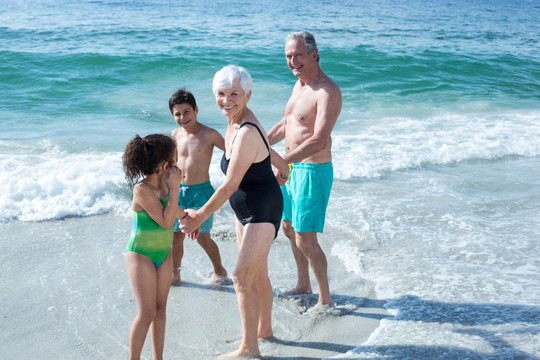 快乐的祖父母和孩子们站在沙滩上