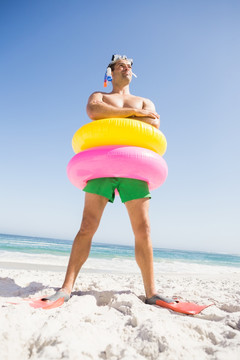 戴着游泳圈站在沙滩上的男人