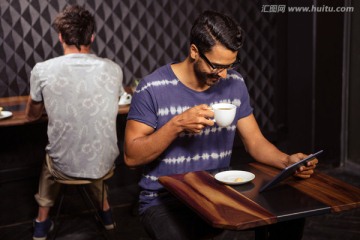 男子使用平板电脑和喝咖啡