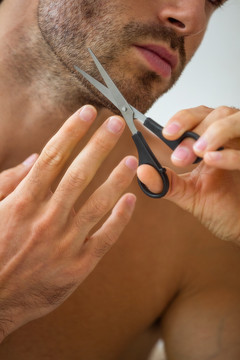 年轻人用剪刀剪胡须