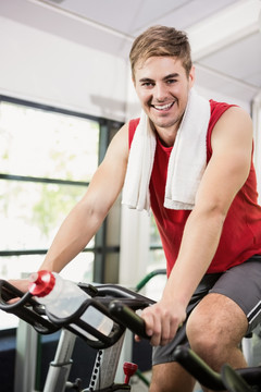 在健身房里骑动感自行车的男人
