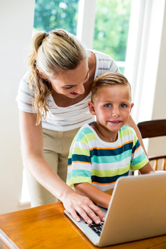 在教儿子使用笔记本电脑的母亲
