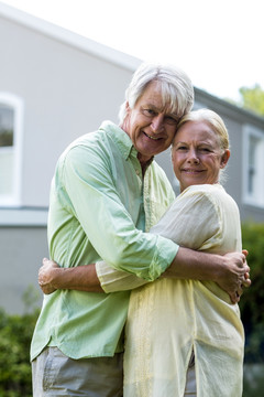 微笑的老夫妇在与院子里拥抱
