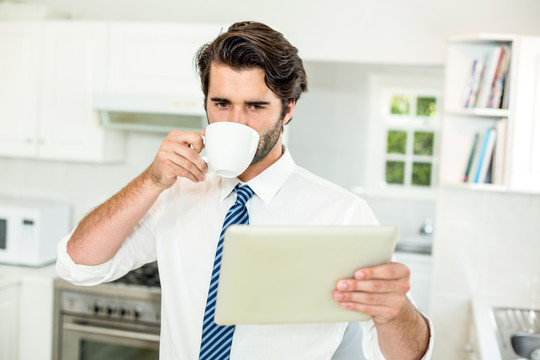边喝咖啡边用平板电脑的男人