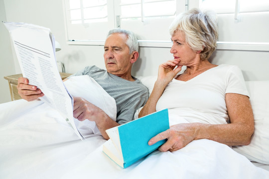 坐在床上看报纸看书的老夫妇