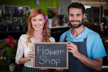 在花店里拿著一塊黑板的夫婦