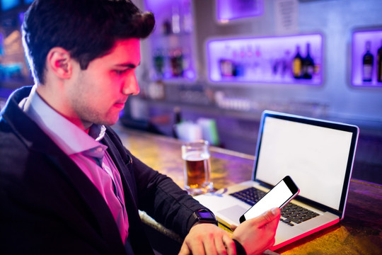在酒吧使用笔记本电脑的商务男人