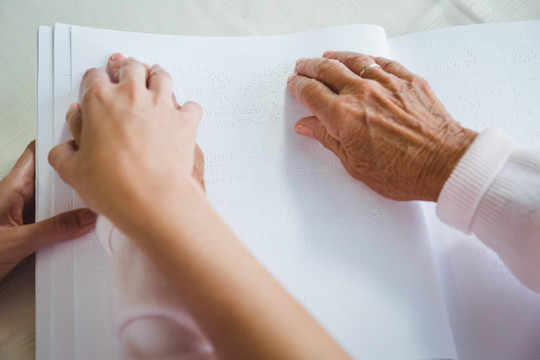 护士帮助老年人盲文阅读