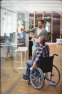 商人坐在轮椅上协助同事贴便利签