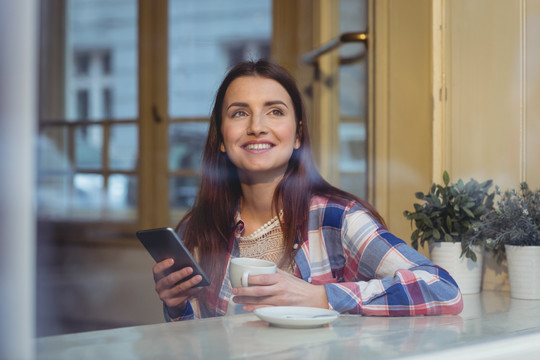 微笑的女人在咖啡馆里用手机