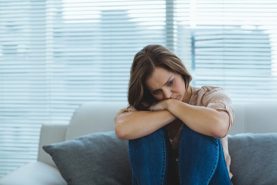 伤心的年轻女人坐在家里的沙发上