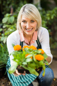 微笑的女园丁拿着一个盆栽