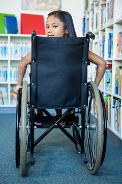 坐在轮椅上在图书馆找书的小学生