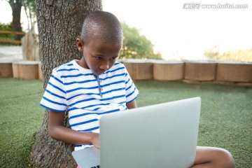 在公园里使用笔记本电脑的男孩