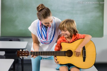 在教室里教男学生弹吉他的女老师