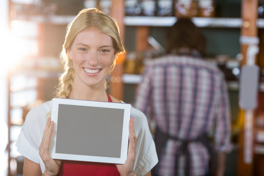 微笑的女员工在超市展示平板电脑