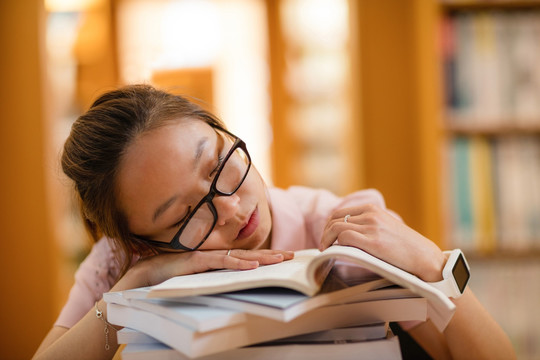年轻的女人睡在图书馆里