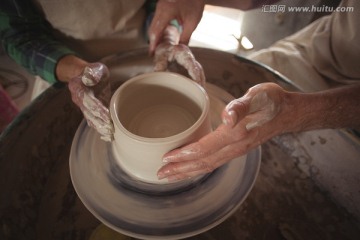 在协助女人做陶器的男陶艺工