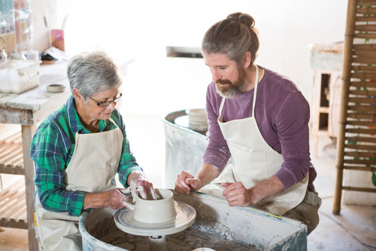 在教老人做陶器的男工人