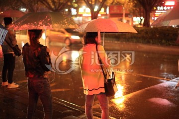 夜晚在路边打雨伞等公交的人们