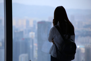 美女大楼落地窗前看风景剪影