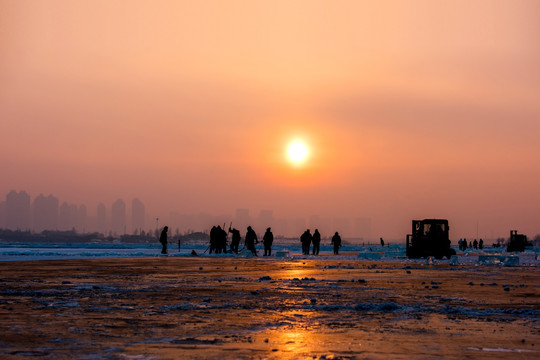 冬季夕阳下江面上的采冰人