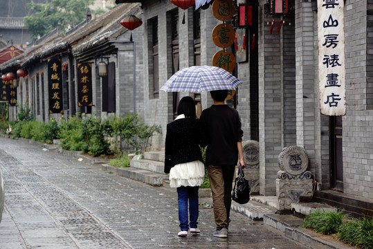 雨中古街打伞的一对恋人