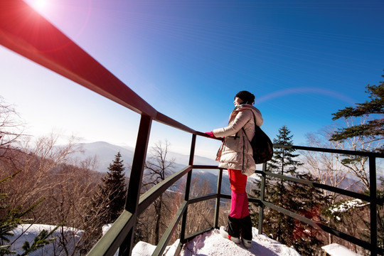 女人站在山顶雪景中远望