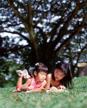 两个孩子躺在草地上看书
