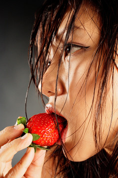 湿着头发的女人在吃一个草莓