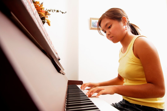 年轻女子坐在钢琴前低头