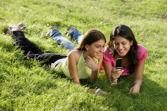 两个十几岁的女孩在公园里看短信