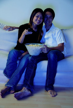 情侣坐在沙发上看电视
