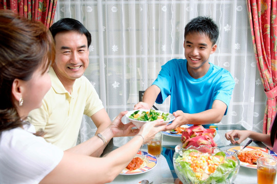 母亲和儿子在餐桌上相互传递食物